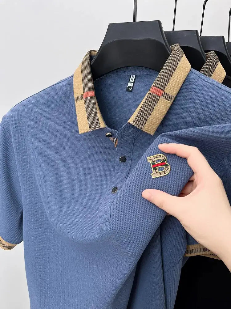 Blue polo shirt with beige plaid collar and B logo patch.