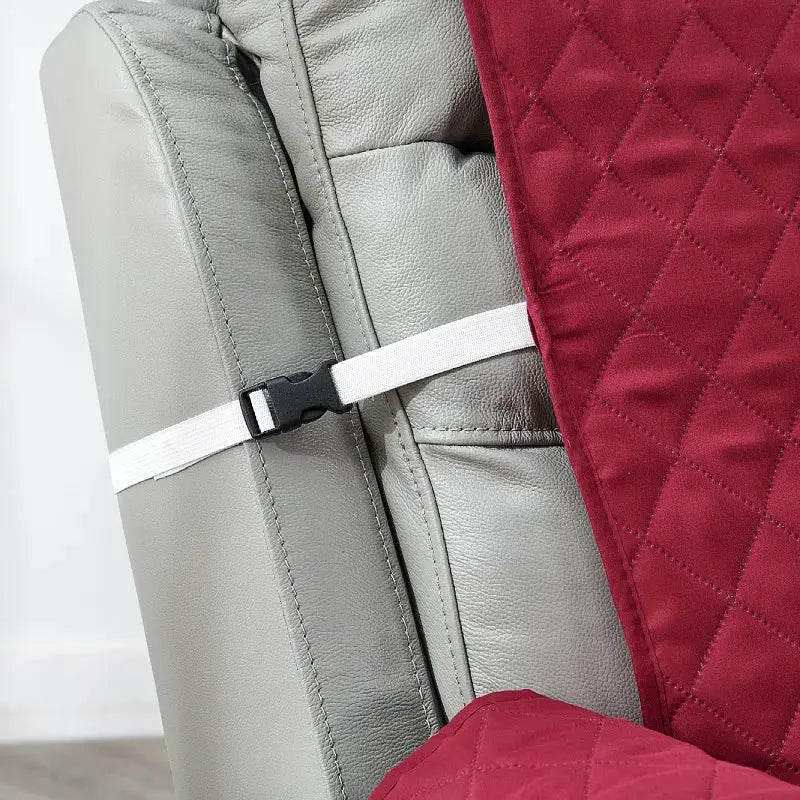 Anti-slip recliner chair cover in maroon quilted fabric with white strap closure on gray leather chair