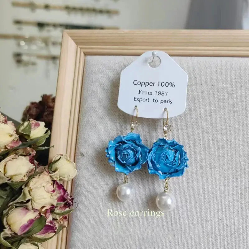 Blue rose epoxy resin earrings with pearl drop pendants and gold-tone hooks, pair