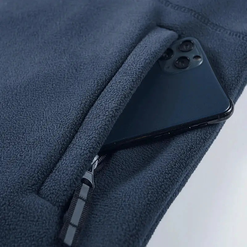 Men's fleece hooded jacket in dark blue by Simples Market with a zip pocket holding a phone.