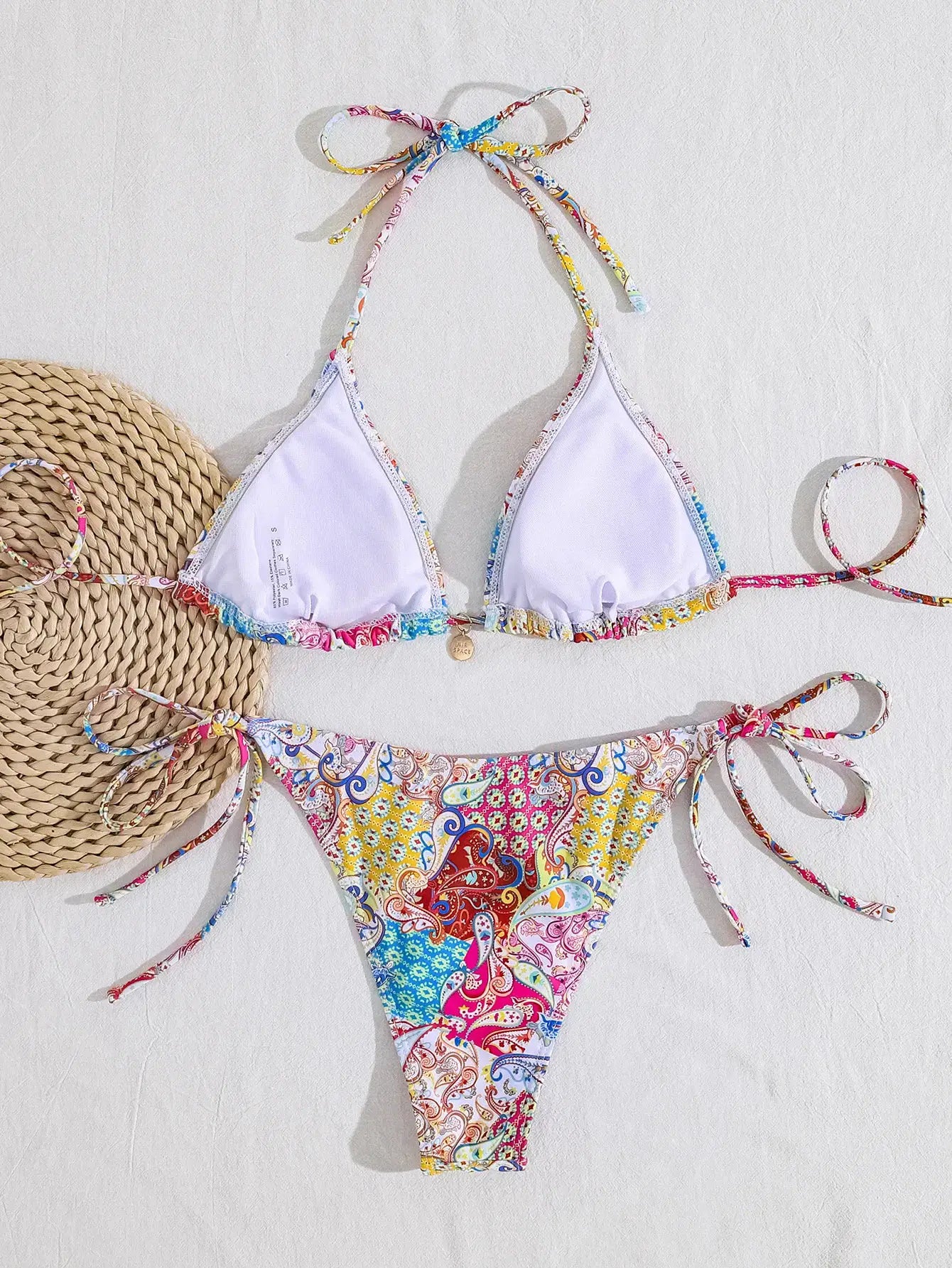 Women's two-piece bikini set with white triangle top and adjustable tie-side paisley-print bottoms.