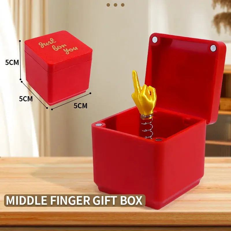 Middle finger prank gift box, red plastic cube with open lid, yellow finger on a spring by Simples Market