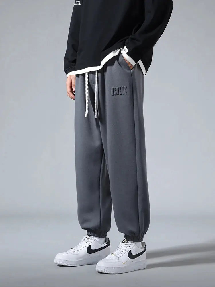 Men's gray cotton-polyester jogger pants with drawstring waist and cuffed ankles, loose hip-hop fit.