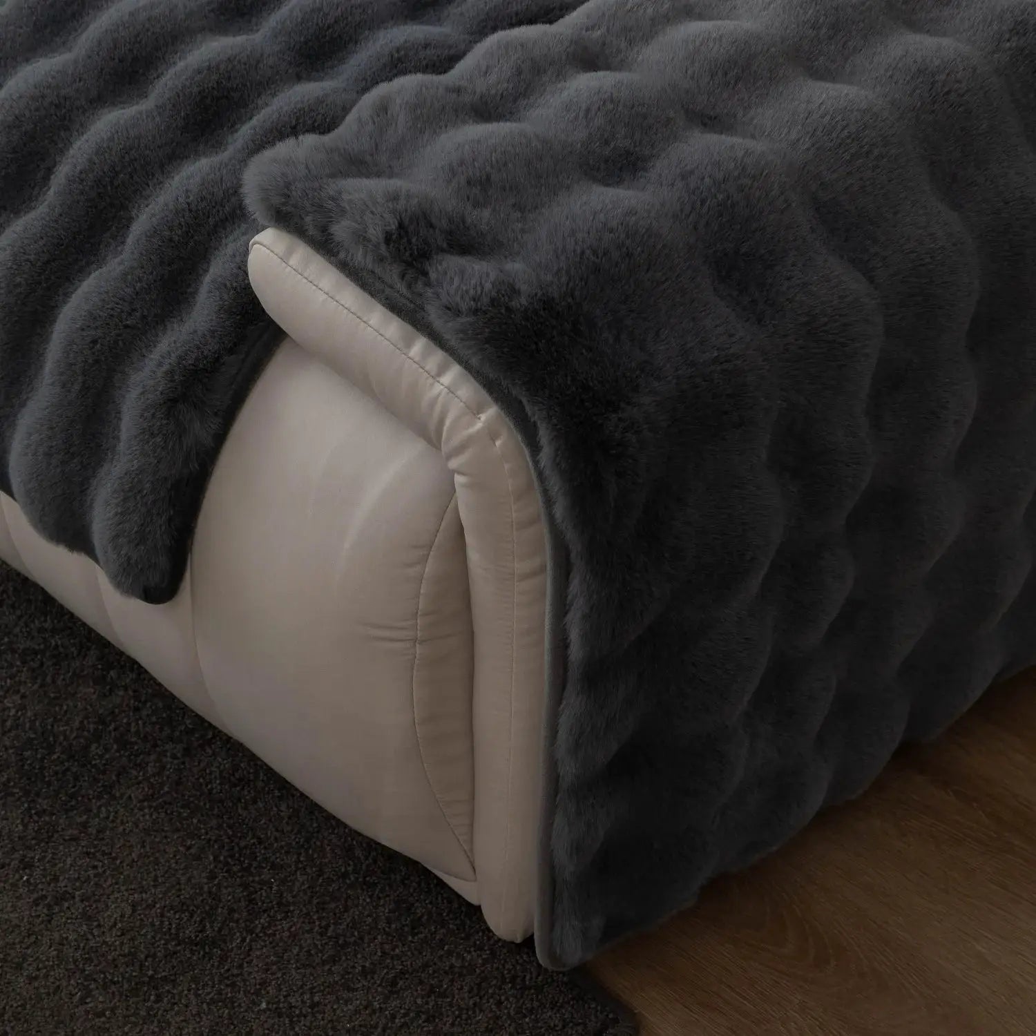 Thick imitation rabbit fur sofa slipcover in dark gray with non-slip backing on a beige sofa