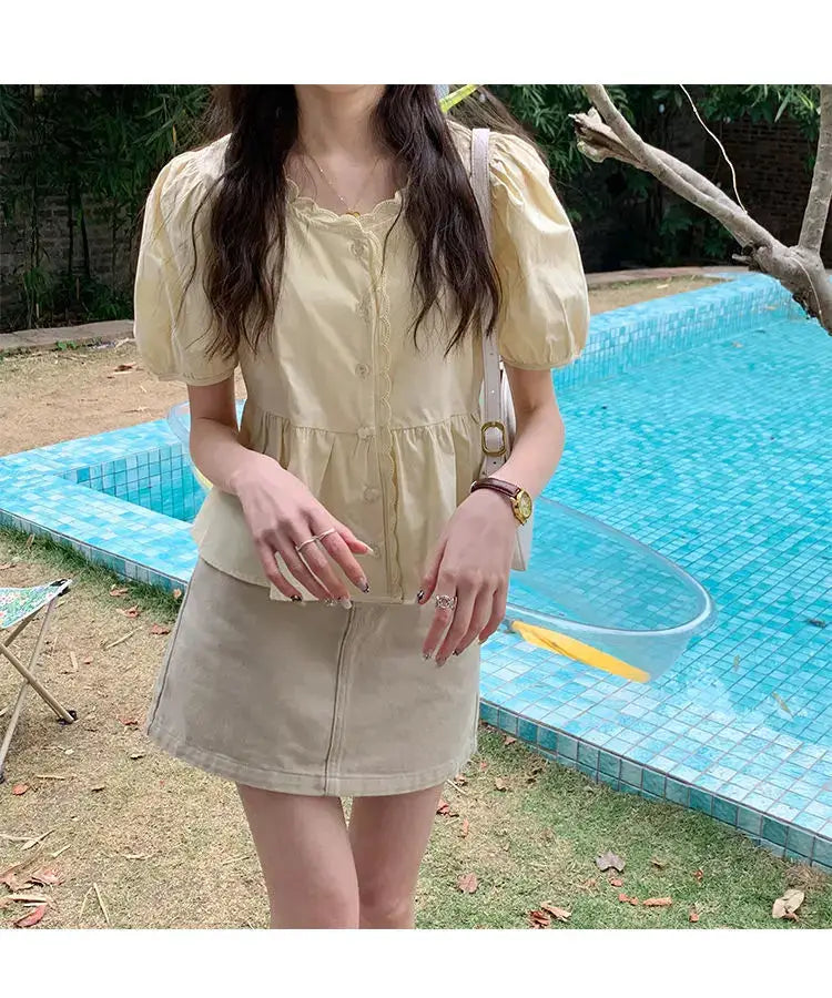 Women's pale yellow puff-sleeve shirt with button front, paired with beige mini skirt