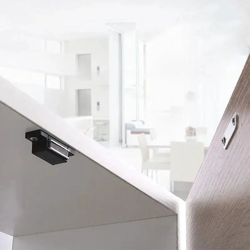 Simples Market cabinet magnetic door lock; black latch mounted on white cabinet door