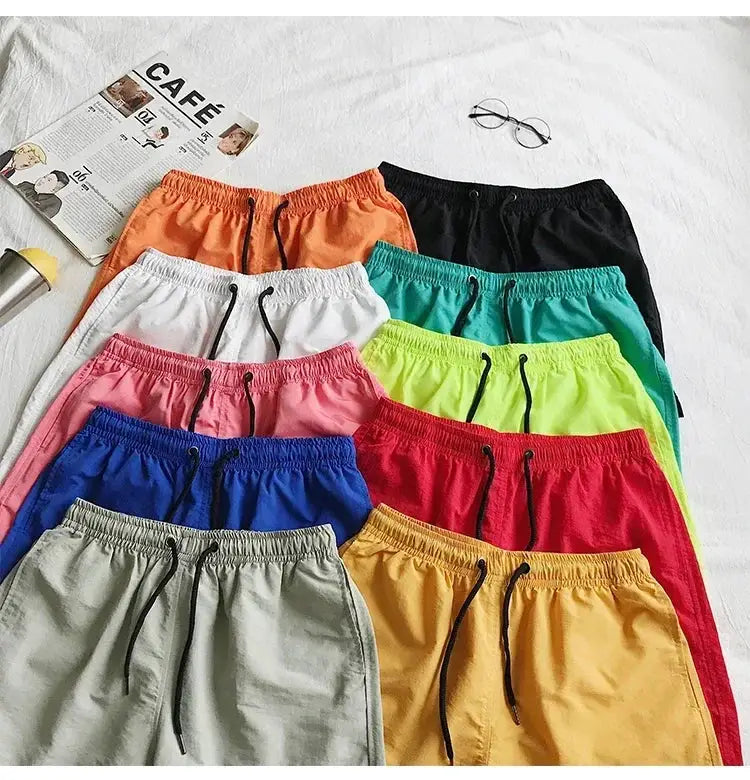 Men's swim shorts set by Simples Market in 12 bright colors laid flat