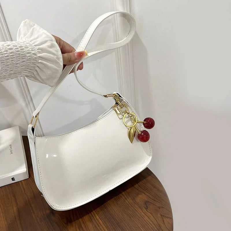 Women's white PU leather shoulder bag with cherry pendant charm and gold hardware.