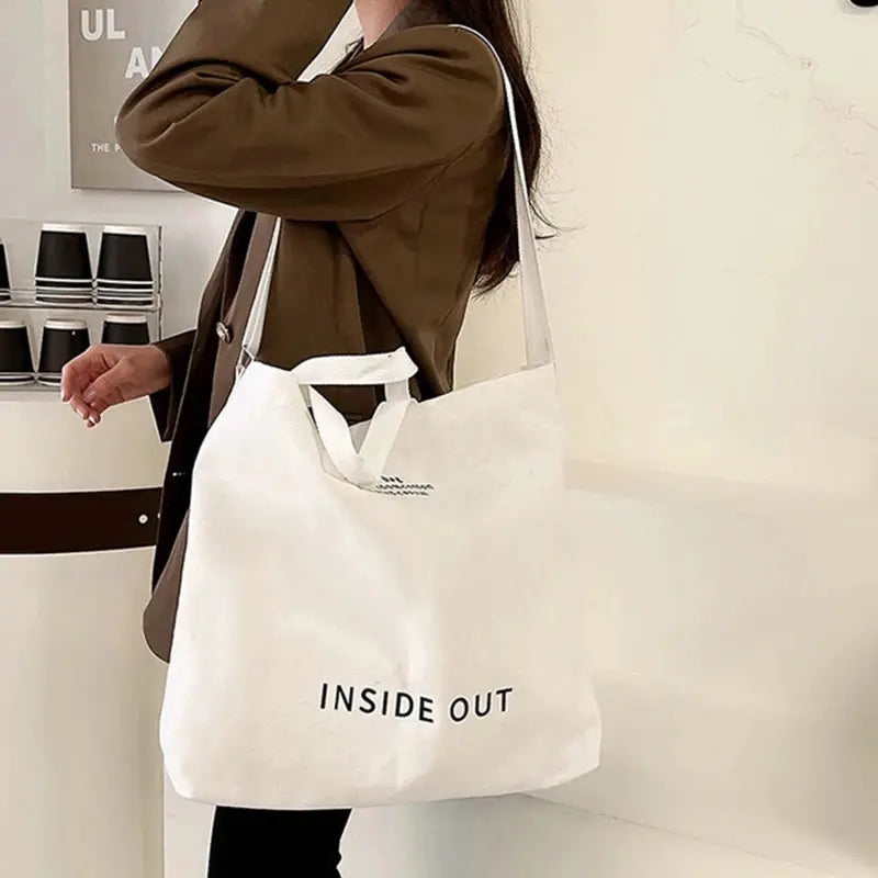 Canvas crossbody bag in white with long strap and short handles, INSIDE OUT.