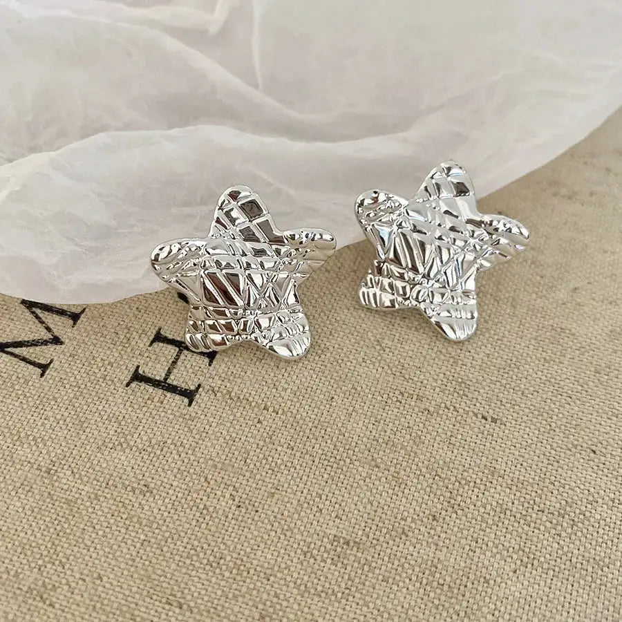 Silver star-shaped stud earrings by Simples Market with textured geometric surface (pair)