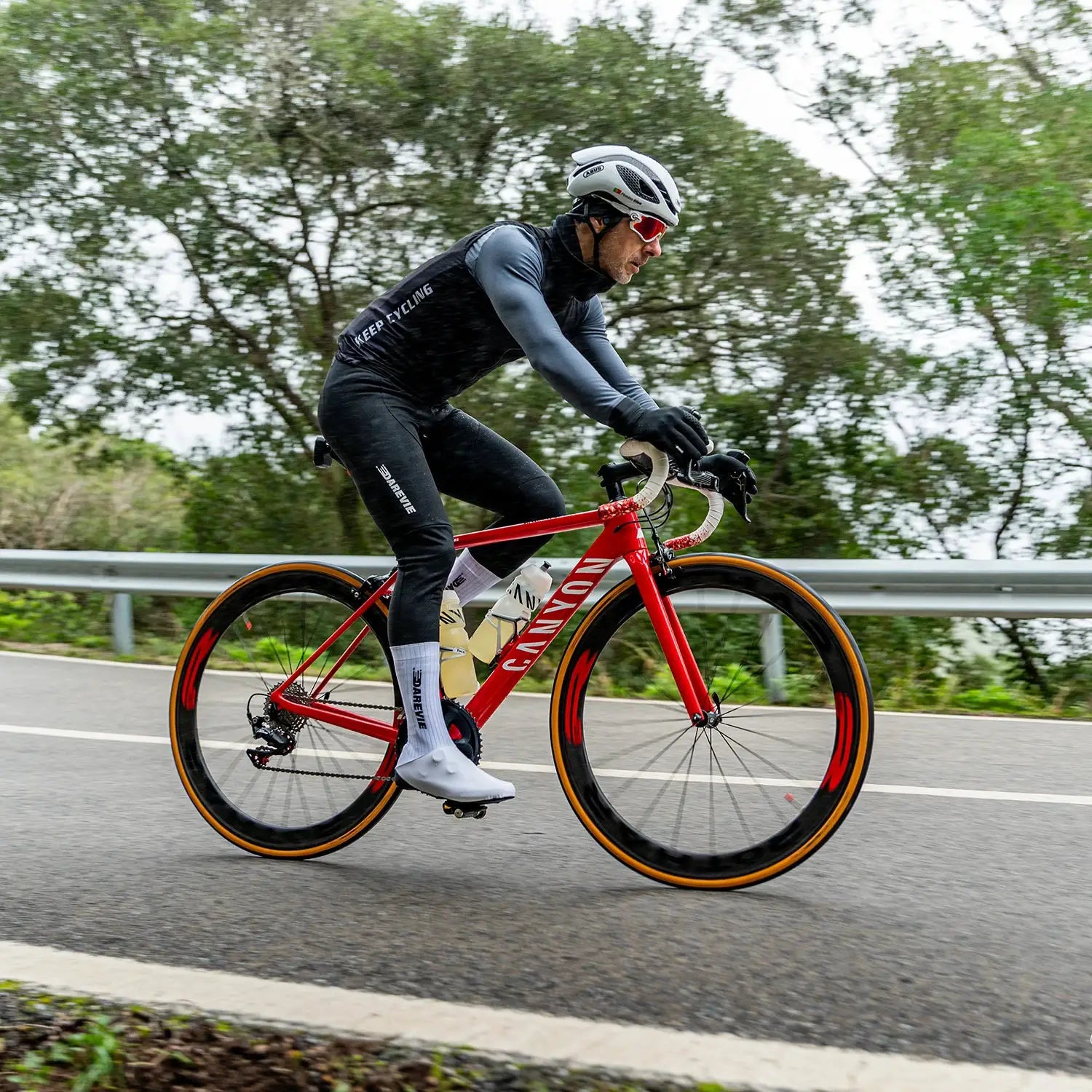 DAREVIE men's winter thermal fleece cycling jersey with long sleeves, worn by cyclist on a red Canyon road bike.