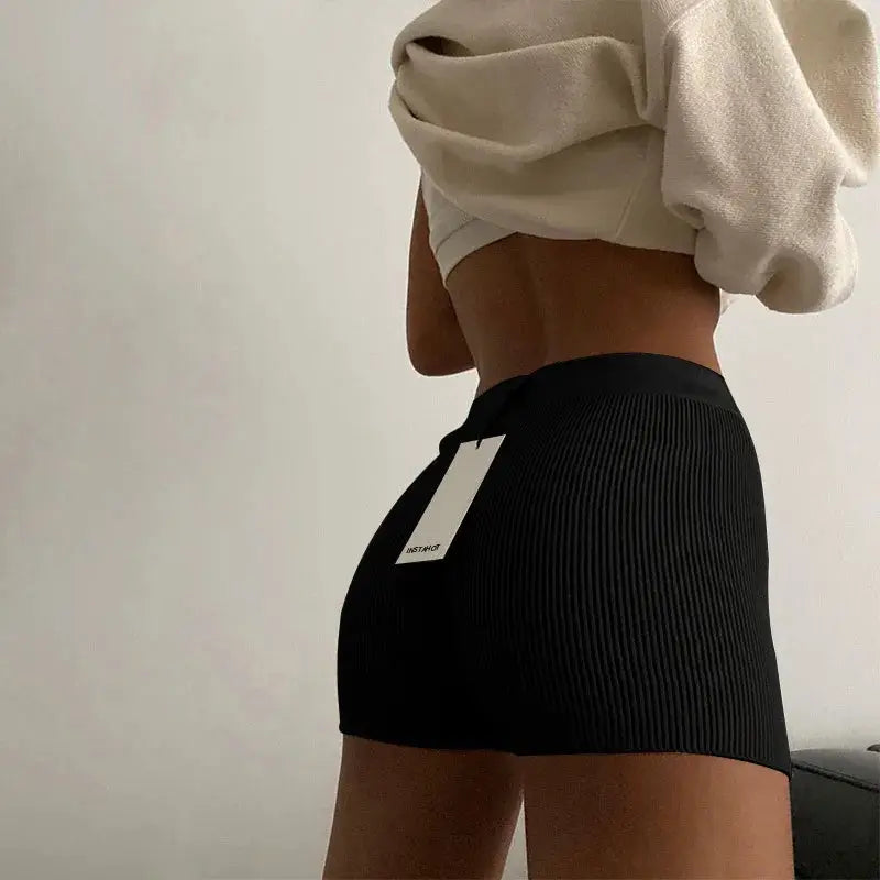 Women's black ribbed high-waist knitted shorts on a model with a visible tag.