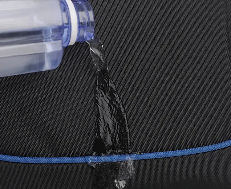 Backpack close-up in black fabric with blue trim; water pours onto the fabric.