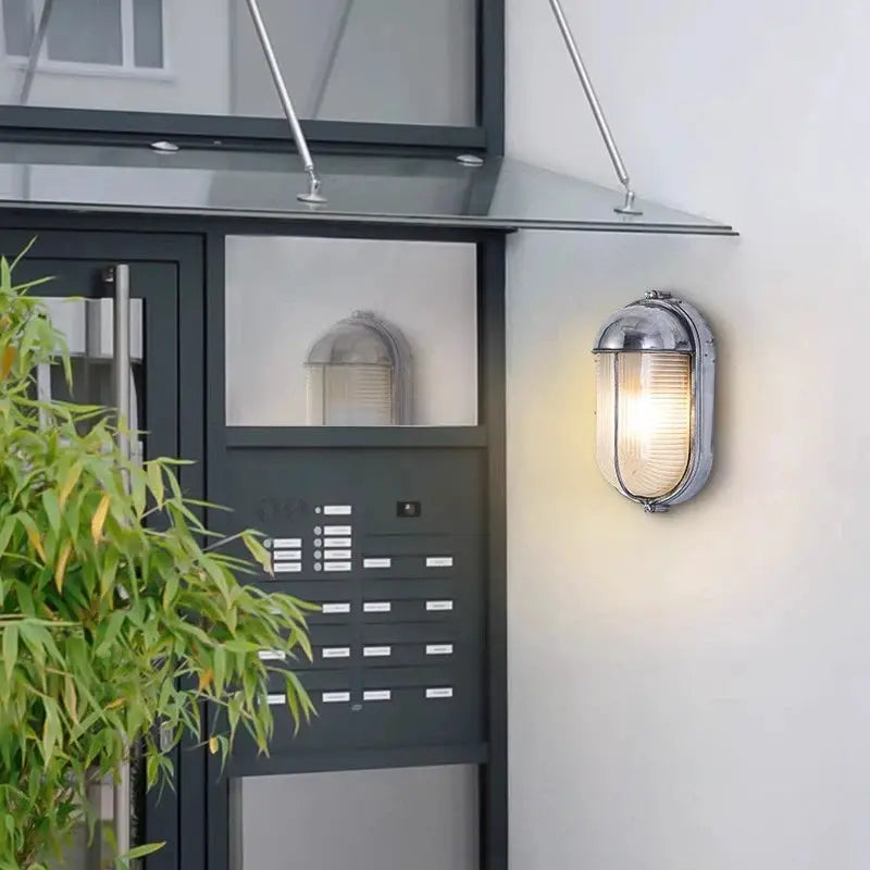 Outdoor retro LED wall light by Simples Market, silver metal with glass shade, E27 sconce