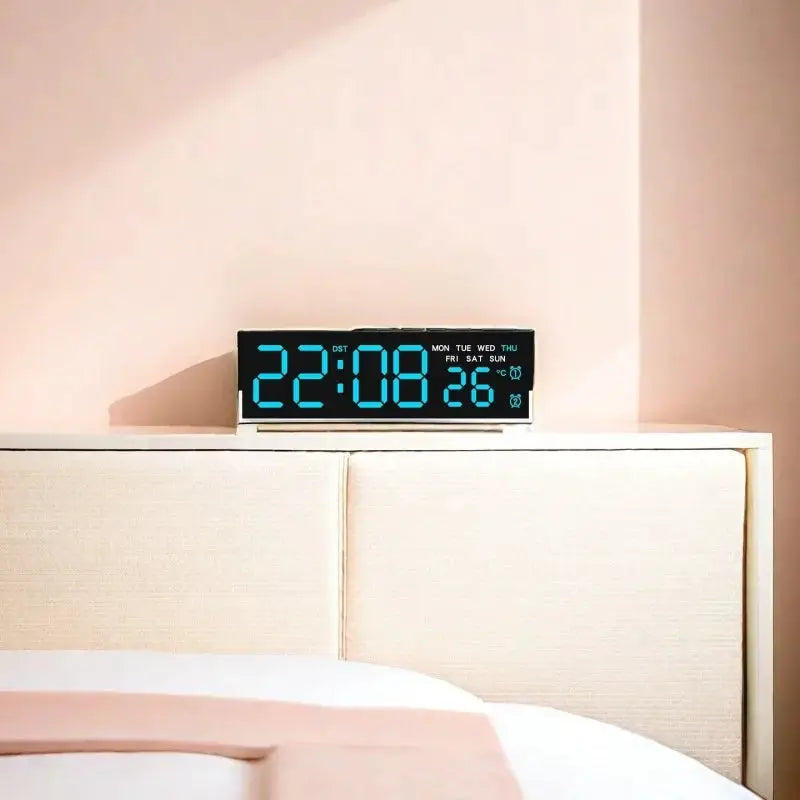 USB-powered digital alarm clock with blue LED display on a bedside table