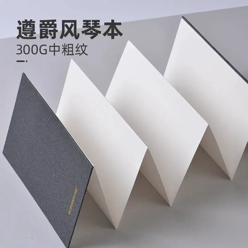Mini watercolor sketchbook with foldable accordion design, white blank pages, dark textured cover.