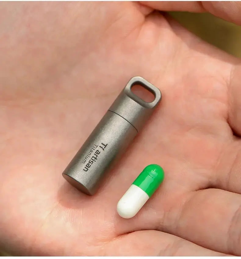 Tiartisan titanium mini pill container with a green-and-white capsule in hand