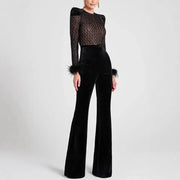 Women's black velvet jumpsuit with sheer lace top, long sleeves, and feathered cuffs; wide-leg silhouette.