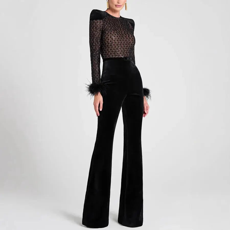 Women's black velvet jumpsuit with sheer lace top, long sleeves, and feathered cuffs; wide-leg silhouette.