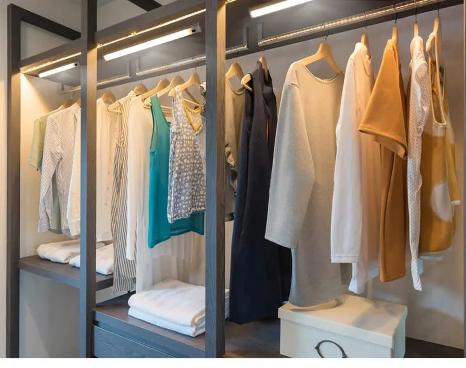 LED wardrobe light strip with PIR motion sensor illuminating a closet with hanging clothes.