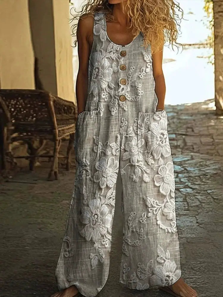 Women's sleeveless jumpsuit in grey linen with large white floral embroidery, front buttons and pockets, wide legs.