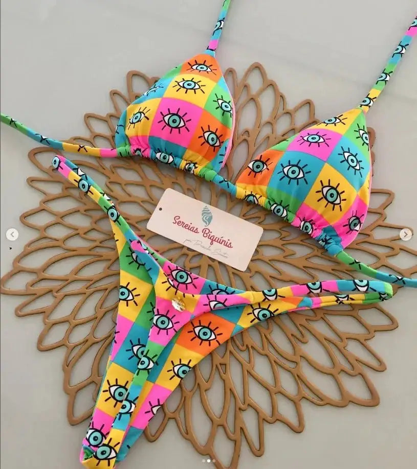 Two-piece bikini set with halter top and thong bottom in a vibrant multicolor eye-print pattern.