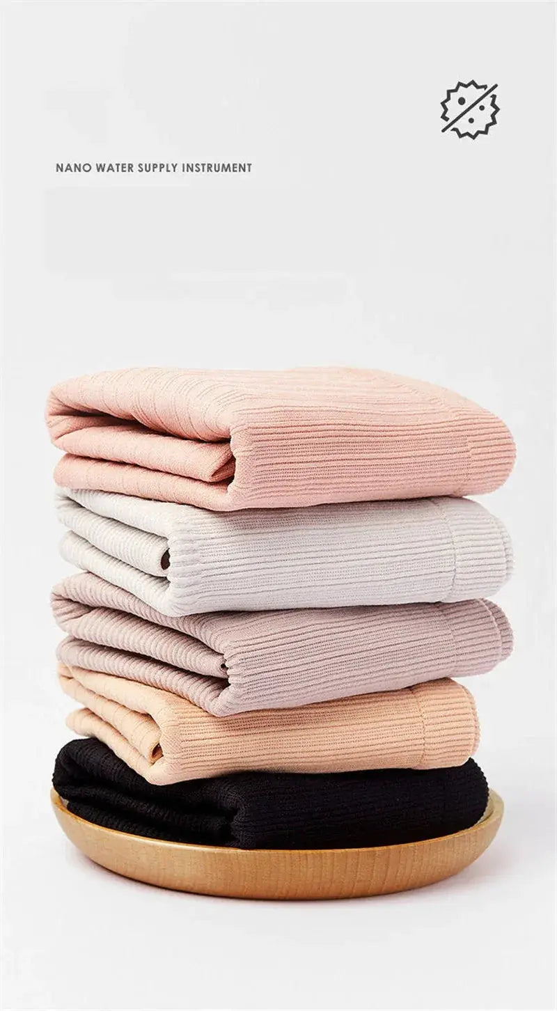 Knit sweaters stacked in pastel colors, six ribbed pieces folded on a wooden plate.