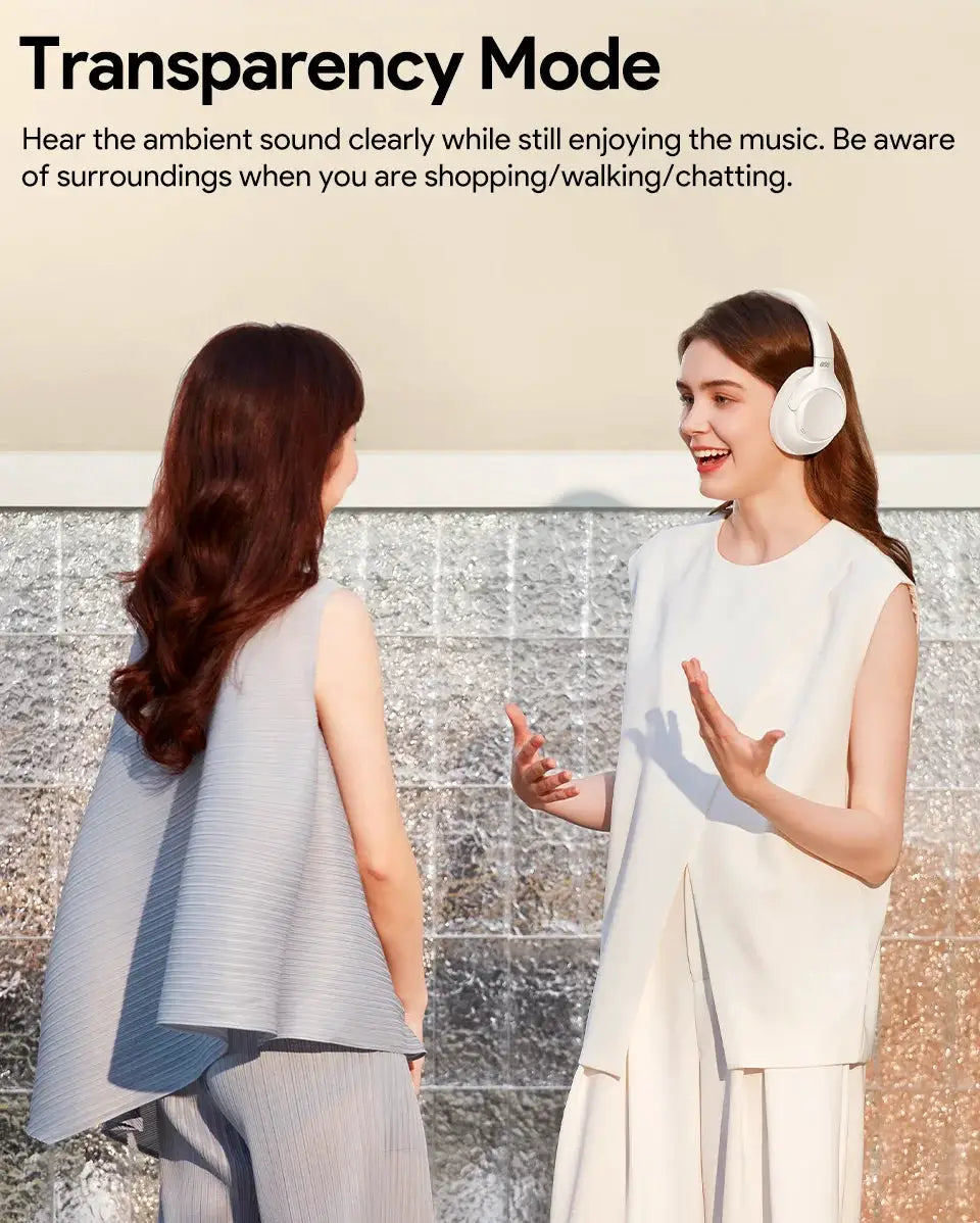 QCY H3 ANC wireless over-ear headphones in white, shown worn by a smiling woman during a conversation.