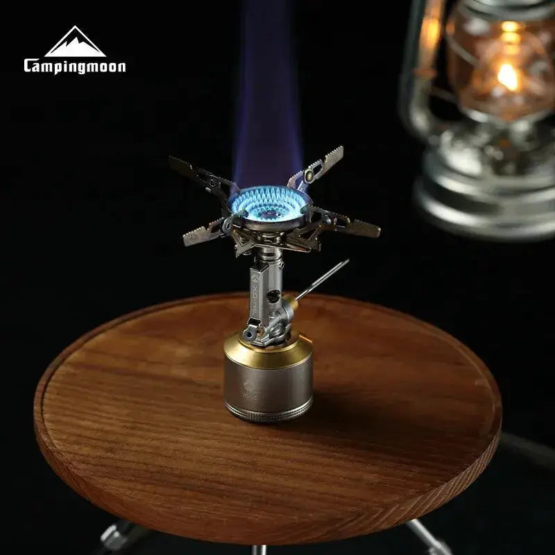 CampingMoon XD-2F portable gas stove with blue flame on a wooden table; CampingMoon logo visible