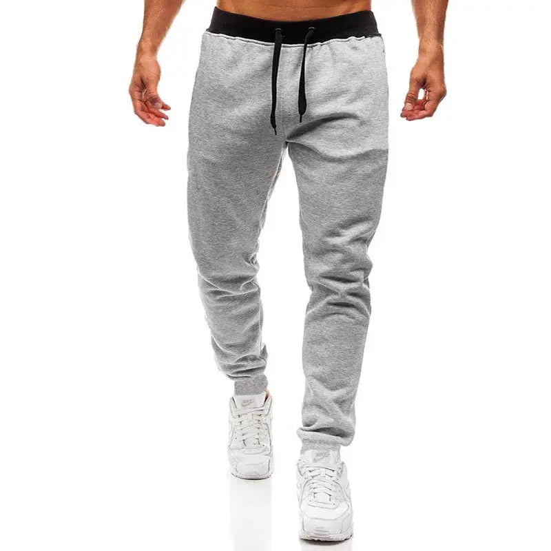 Men's gray joggers with black drawstring waistband, cuffed ankles, loose straight-leg sports pants.