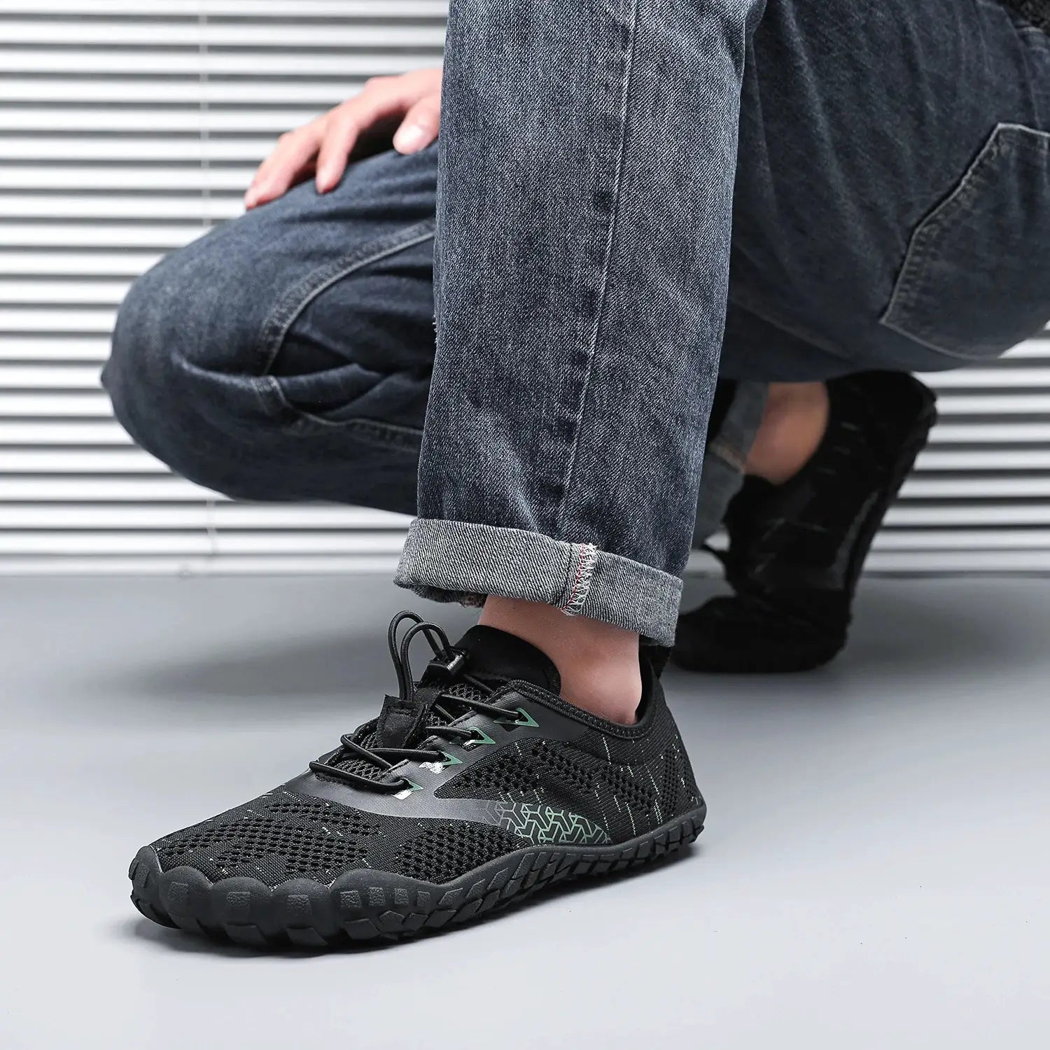 Men's trail running shoe, minimalist barefoot style, black mesh with green accents