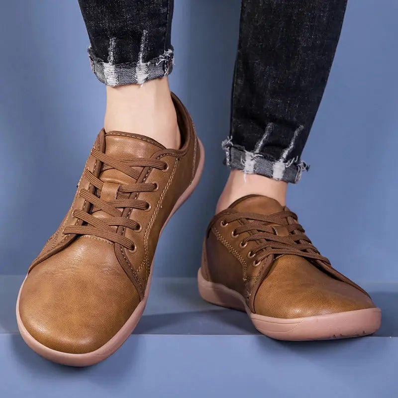 Barefoot shoes, brown with lace-up front and pink sole, worn with rolled jeans