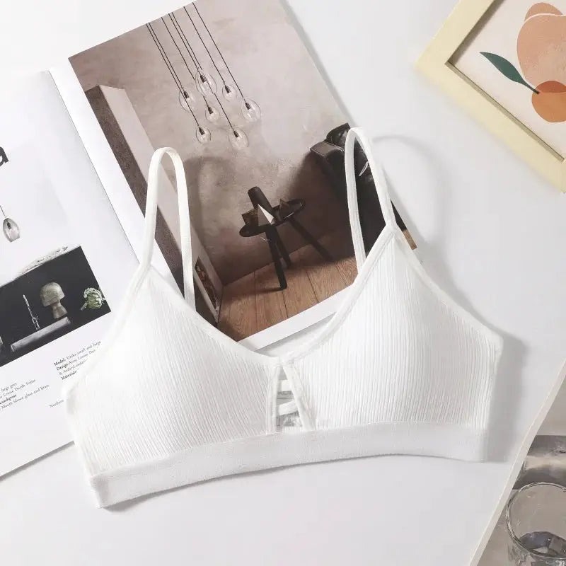 Women's ribbed hollow-out bralette wireless with thin straps, white, on a magazine backdrop.