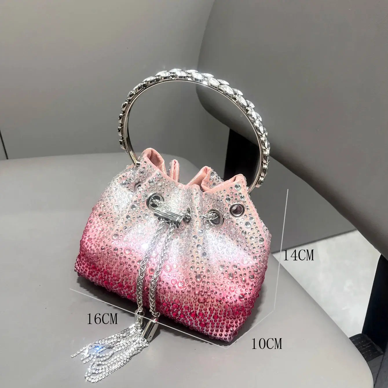 Pink gradient rhinestone evening clutch with a crystal-studded circular silver handle and dangling crystal tassel