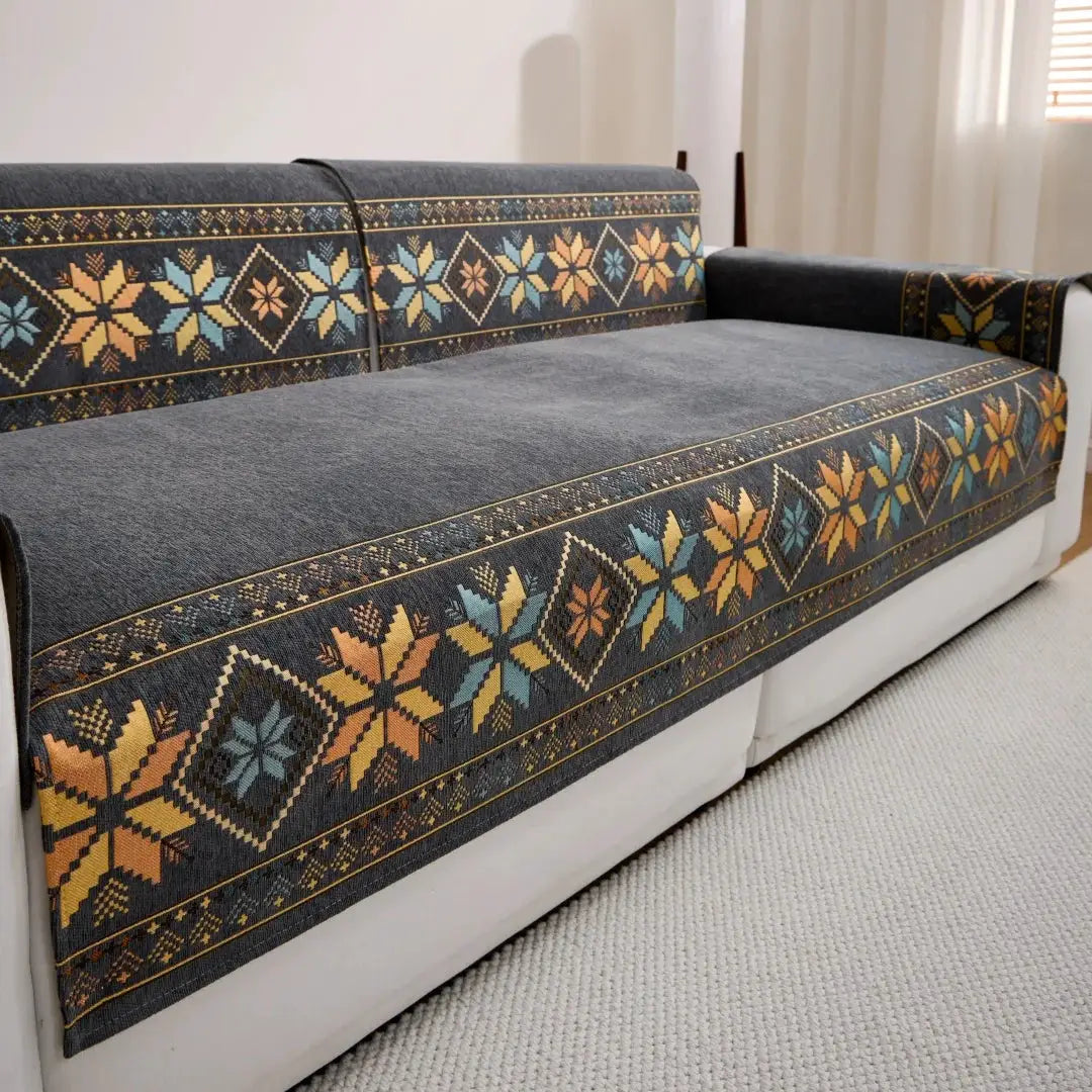 One-piece Bohemian jacquard chenille sofa cover on a dark blue sofa with orange, teal and yellow geometric patterns