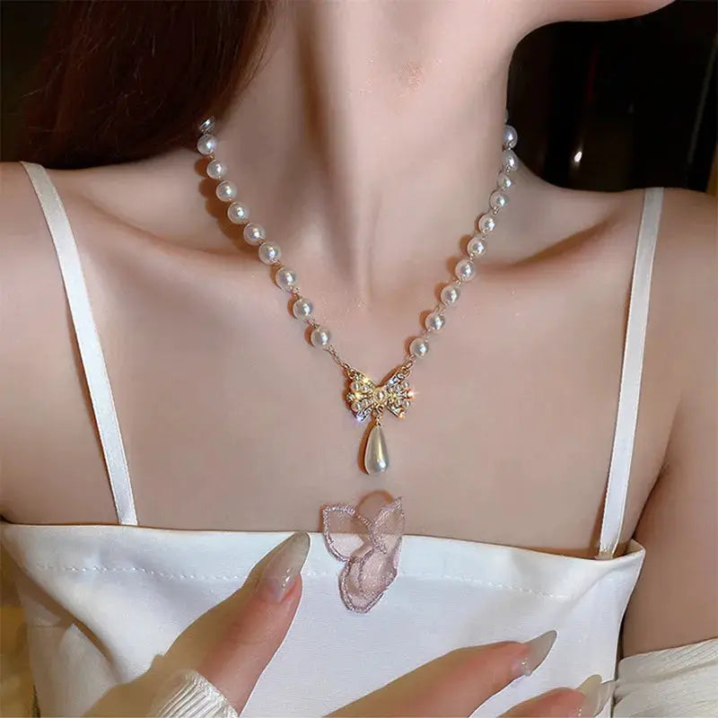 Pearl bead choker necklace by Simples Market with gold bow pendant and teardrop pearl charm