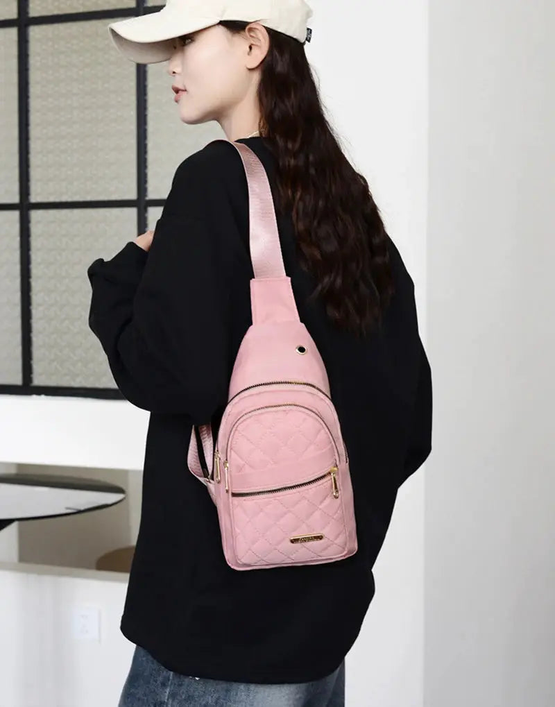 Pink quilted backpack with front zip pockets, gold hardware, and crossbody strap by Simples Market