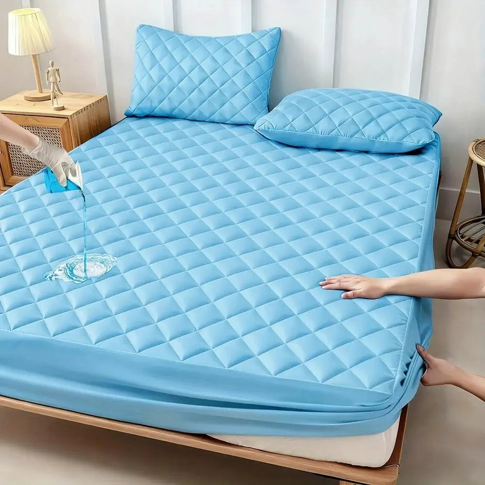 Blue quilted waterproof mattress protector on bed with two matching pillows