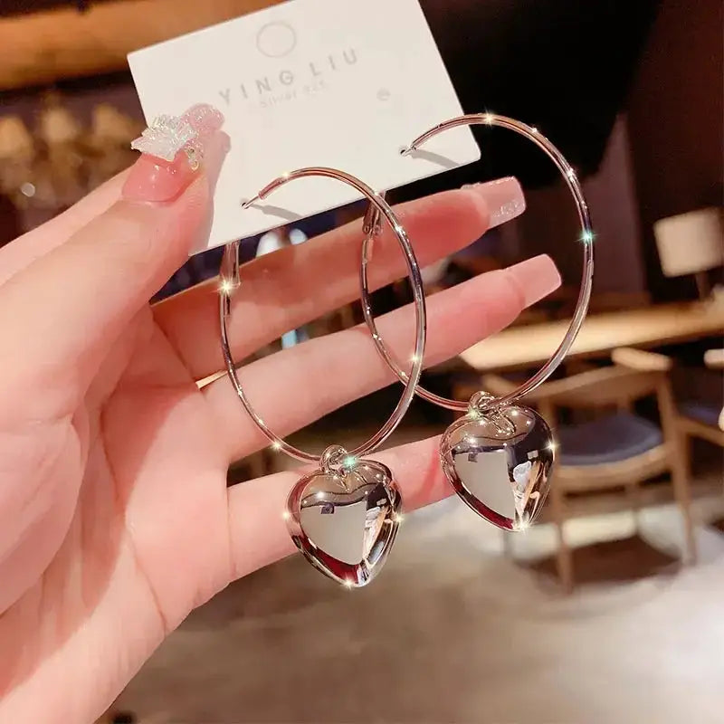 Pair of silver-tone zinc alloy hoop earrings with heart pendants for women