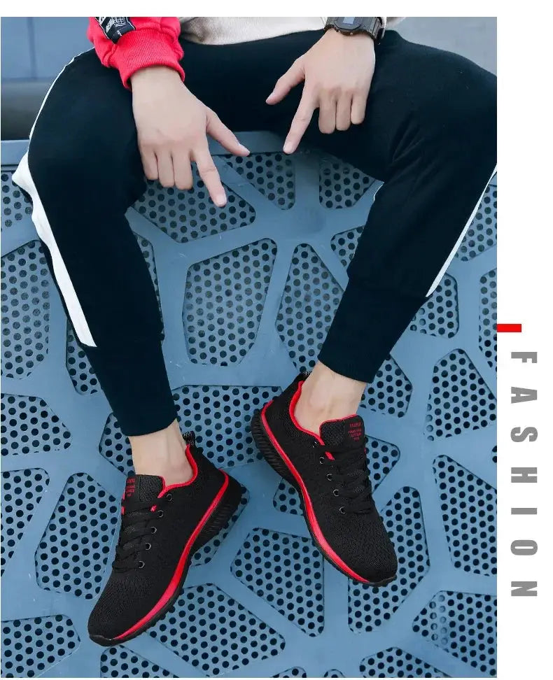 Men's running knit sneakers in black with red trim and sole, worn with black joggers.