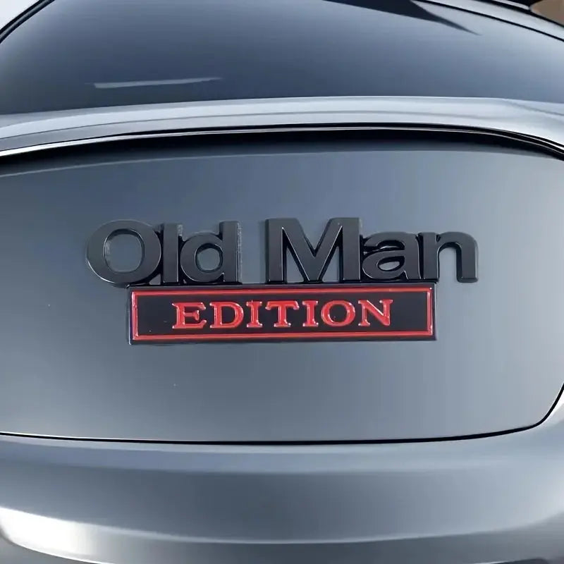 Old Man Edition 3D car badge sticker on a blue trunk; black lettering with red Edition label.