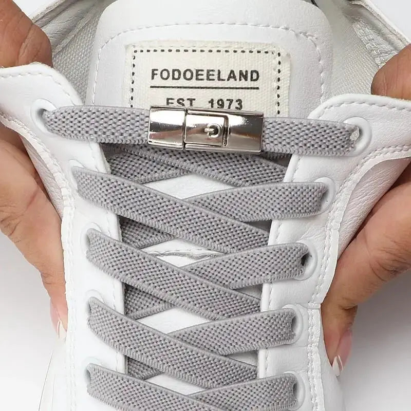No-tie elastic press-lock shoelaces on white sneaker with gray flat laces and metal clasp