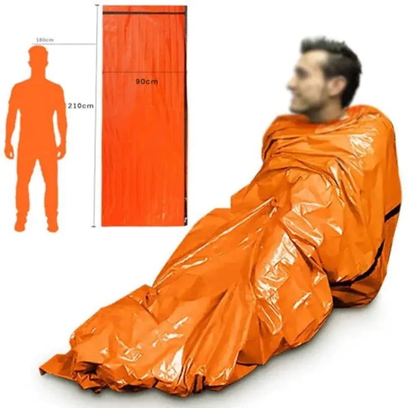 Orange emergency survival sleeping bag for outdoor camping; waterproof Mylar blanket shown with a person inside.