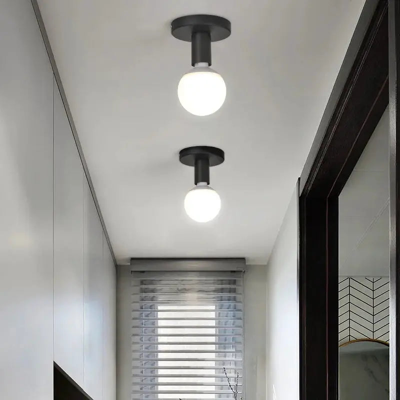Pair of minimalist black E27 ceiling light fixtures with globe bulbs in a hallway.