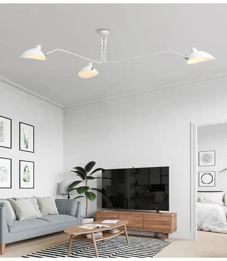 White three-arm spider pendant LED ceiling light with adjustable shades in a modern living room.
