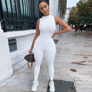 Pencil jumpsuit for women, white sleeveless slim-fit activewear; model outdoors with small brown handbag.