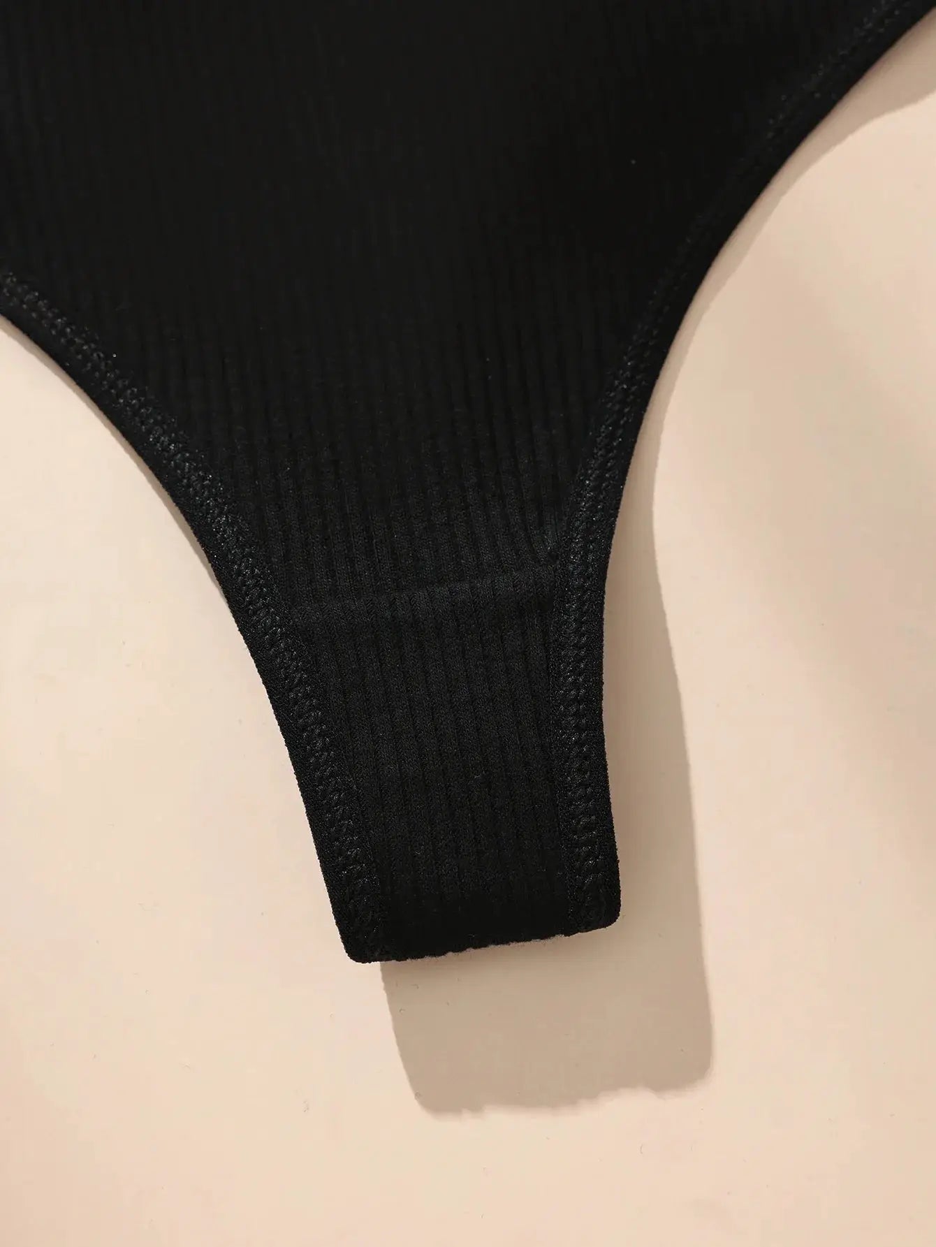 Women's black cotton thong underwear with ribbed fabric, close-up view