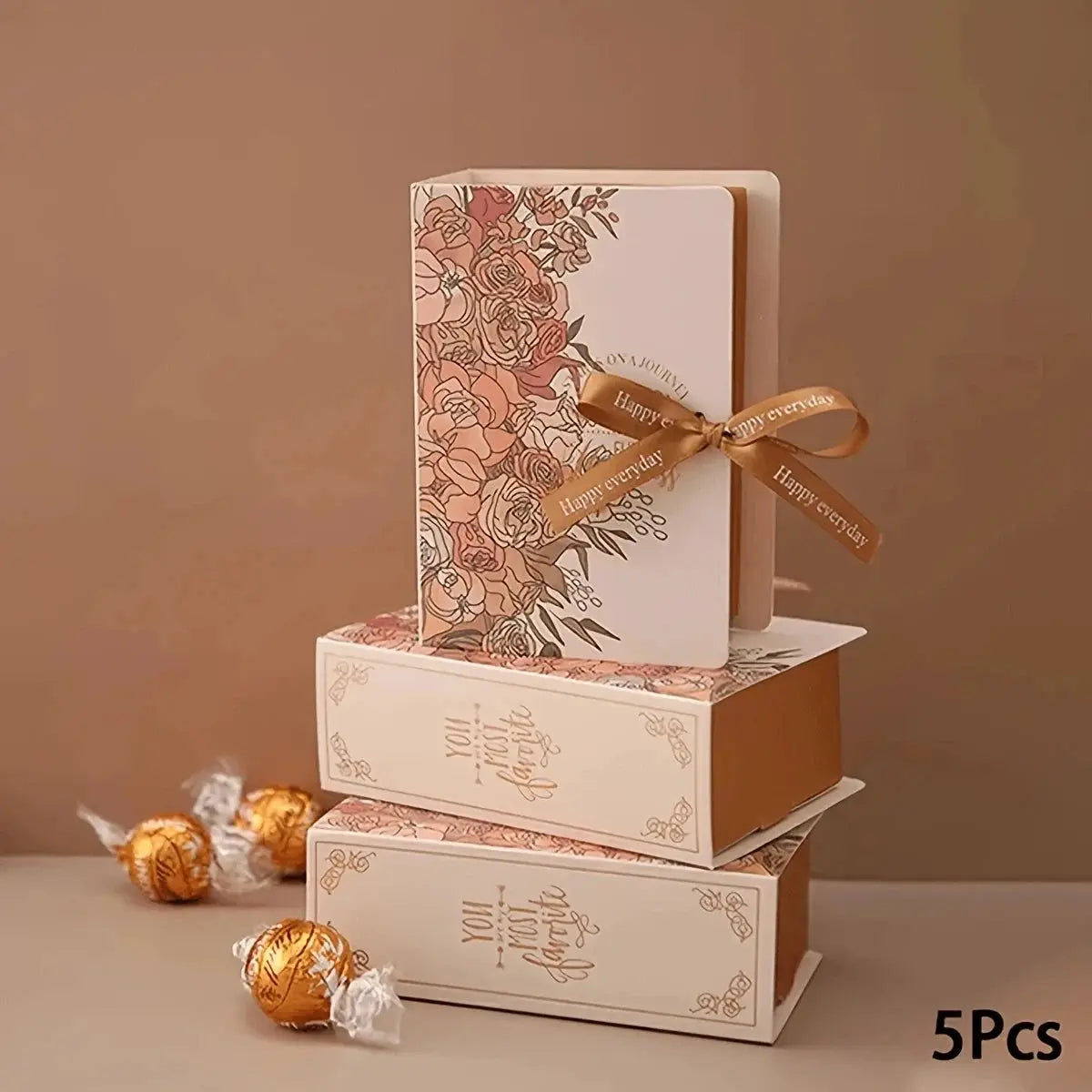 5Pcs book-shaped gift boxes with floral print and satin ribbon, rose-gold accents; chocolates nearby