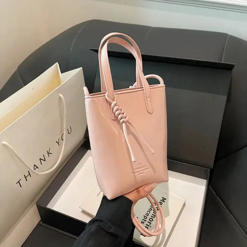 Mini pink PU leather crossbody bag with top handles and knotted tie detail.