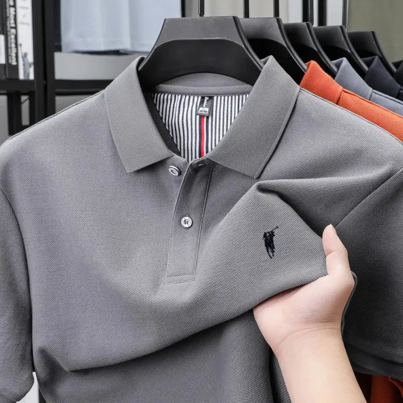 Grey cotton polo shirt with small black pony embroidery on chest; five polo shirts on hangers in assorted colors